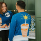Man and woman hanging out in kitchen with green cabinets wearing Whataburger holiday sweaters